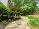 A winding stone pathway adorned with pebbles leads through the lush backyard at 1501 Chatsworth Ln, Raleigh, NC 27614