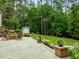 Serene backyard patio with stone pavers, lovely landscaping, fire pit, and shed with surrounding lush greenery at 1501 Chatsworth Ln, Raleigh, NC 27614