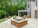 Brick fire pit area on stone patio with comfortable seating and view of the pizza oven in the background at 1501 Chatsworth Ln, Raleigh, NC 27614
