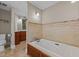 Bright bathroom features a soaking tub and tiled walls, plus wood storage at 1501 Chatsworth Ln, Raleigh, NC 27614