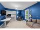Vibrant blue bedroom featuring a sofa, recliner, desk, and a mounted guitar on the wall at 1501 Chatsworth Ln, Raleigh, NC 27614