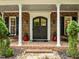 Inviting front porch with brick columns, swing, and a grand front door flanked by planters and a rocking chair at 1501 Chatsworth Ln, Raleigh, NC 27614