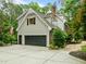 Two-car garage with black door and paved driveway, side entrance, and American flag at 1501 Chatsworth Ln, Raleigh, NC 27614