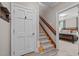 Hallway with door, wood railing staircase, and view into a bedroom with a bed at 1501 Chatsworth Ln, Raleigh, NC 27614