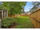 Fenced backyard featuring a lush green lawn with mature trees and shrubs at 151 Lake Pine Dr, Cary, NC 27511