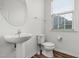 Clean half bath features a white pedestal sink and toilet, complemented by a window for natural light at 1728 Shady Oaks Dr, Wendell, NC 27591