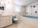 Colorful vintage bathroom features blue bathtub and toilet, white tile walls, and stained glass window at 183 Birnamwood Dr, Chapel Hill, NC 27516
