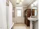 Vintage bathroom featuring a pedestal sink, wooden storage cabinet, patterned floors, and a standing tub with shower at 183 Birnamwood Dr, Chapel Hill, NC 27516
