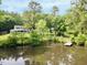 Secluded home featuring a pond and dock surrounded by mature trees creating a private, picturesque setting at 183 Birnamwood Dr, Chapel Hill, NC 27516