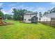 Expansive backyard featuring lush green lawn, screened porch and wooden playground, all enclosed by a wood fence at 20 Scotland Dr, Youngsville, NC 27596