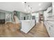 Open kitchen with white cabinets, marble counters, and stainless appliances, adjoining a staircase and hardwood floors at 20 Scotland Dr, Youngsville, NC 27596
