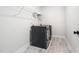 Modern laundry room featuring tile flooring, overhead shelving, and dark washer and dryer at 20 Scotland Dr, Youngsville, NC 27596