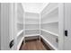 Well-organized walk-in pantry featuring ample white shelving and wood flooring for efficient storage at 20 Scotland Dr, Youngsville, NC 27596