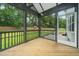 Inviting screened porch with wooden floors, offering views of the lush backyard and outdoor play area at 20 Scotland Dr, Youngsville, NC 27596