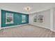 Spacious bedroom featuring three windows, neutral carpet, and a stylish teal accent wall for a modern look at 2018 Morehead Hill Ct, Durham, NC 27703
