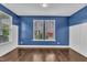 Bright living room with hardwood floors, blue accent wall, white trim and large window at 2018 Morehead Hill Ct, Durham, NC 27703