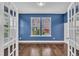 Bright living room with hardwood floors, blue accent wall, white trim and two windows at 2018 Morehead Hill Ct, Durham, NC 27703