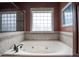 A luxurious bathroom featuring a large soaking tub with a tiled surround and decorative windows, offering a spa-like retreat at 2109 Taramar Ln, Zebulon, NC 27597