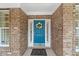 Close-up of an inviting blue front door with wreath, brick surround, and welcome mat at 220 Cole Valley Dr, Cary, NC 27513
