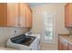 Modern laundry room with white washer and dryer, natural light, and wooden cabinets at 220 Cole Valley Dr, Cary, NC 27513