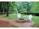 Backyard with fire pit, brick patio, and wooden chairs surrounded by lush greenery at 2216 Countrywood North Rd, Raleigh, NC 27615
