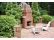 Outdoor patio with brick fireplace, seating, and lush landscaping at 2216 Countrywood North Rd, Raleigh, NC 27615