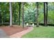 Inviting backyard featuring a charming brick fire pit and serene wooded views at 2216 Countrywood North Rd, Raleigh, NC 27615