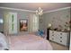 Bedroom with a pink bed, shuttered windows, chandelier, and butterfly wall decorations at 2216 Countrywood North Rd, Raleigh, NC 27615