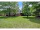 Expansive backyard with lush green lawn, mature trees, and view of the house and deck at 225 Norwalk St, Holly Springs, NC 27540