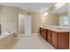 Elegant bathroom featuring double vanity, large mirror, soaking tub, and tile flooring at 225 Norwalk St, Holly Springs, NC 27540