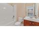 Bright bathroom with white tiled tub/shower combination and cherry vanity at 225 Norwalk St, Holly Springs, NC 27540