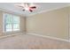 Neutral bedroom features light carpet, a window for natural light, and a ceiling fan at 225 Norwalk St, Holly Springs, NC 27540