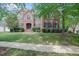 Beautiful two-story brick home with manicured lawn and mature landscaping and a sidewalk at 225 Norwalk St, Holly Springs, NC 27540
