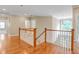 Hallway with hardwood floors and white railing overlooking the foyer and chandelier at 225 Norwalk St, Holly Springs, NC 27540