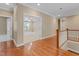 Hallway with hardwood flooring and a doorway view into a bedroom with a ceiling fan and neutral carpet at 225 Norwalk St, Holly Springs, NC 27540