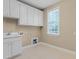 Functional laundry room with white cabinets, sink, window and tile flooring at 225 Norwalk St, Holly Springs, NC 27540