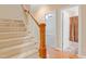 Carpeted staircase with white risers, wooden handrail, and views of a bathroom and living room at 225 Norwalk St, Holly Springs, NC 27540
