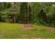 Serene backyard featuring lush greenery and a cozy brick fire pit for outdoor gatherings at 231 Harris Rd, Smithfield, NC 27577