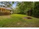 Lush backyard featuring a wooden deck, green lawn, and a brick fire pit at 231 Harris Rd, Smithfield, NC 27577
