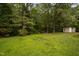 Picturesque backyard with mature trees, green lawn, and a brick fire pit at 231 Harris Rd, Smithfield, NC 27577