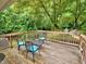 An outdoor wooden deck featuring a table, four chairs with blue cushions, and a view of the lush backyard at 2409 Derby Dr, Raleigh, NC 27610