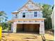 Unfinished two-story home exterior showcasing the frame with an attached two-car garage and lumber on the front lawn at 243 Steel Springs Ln # 25, Angier, NC 27501