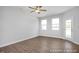 Empty room with hardwood floors, two windows, ceiling fan and a door to the backyard at 3916 Well Fleet Dr, Fuquay Varina, NC 27526