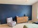 Stylish bedroom with a trendy blue accent wall, dresser, and comfortable chair at 4097 Cordiality Church Rd, Nashville, NC 27856
