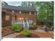 Rear exterior view of a brick home with a cozy backyard patio, deck, and mature trees at 45 Birnham Ln, Durham, NC 27707