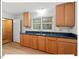 Well-lit kitchen features wood cabinets, granite countertops, and a stainless steel sink with a view to the backyard at 45 Birnham Ln, Durham, NC 27707