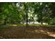 Shaded backyard with mature trees, a view of the house, and a glimpse of the wooden deck at 519 W Raleigh St, Siler City, NC 27344