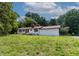 Exterior view of a single-story home with white siding, a red roof, and green lawn on a sunny day at 519 W Raleigh St, Siler City, NC 27344