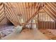 Large unfinished attic space with wooden beams, insulation, and windows at 5233 Greymoss Ln, Apex, NC 27539