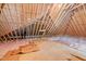 Unfinished attic featuring exposed wooden beams, insulation, and flooring at 5233 Greymoss Ln, Apex, NC 27539